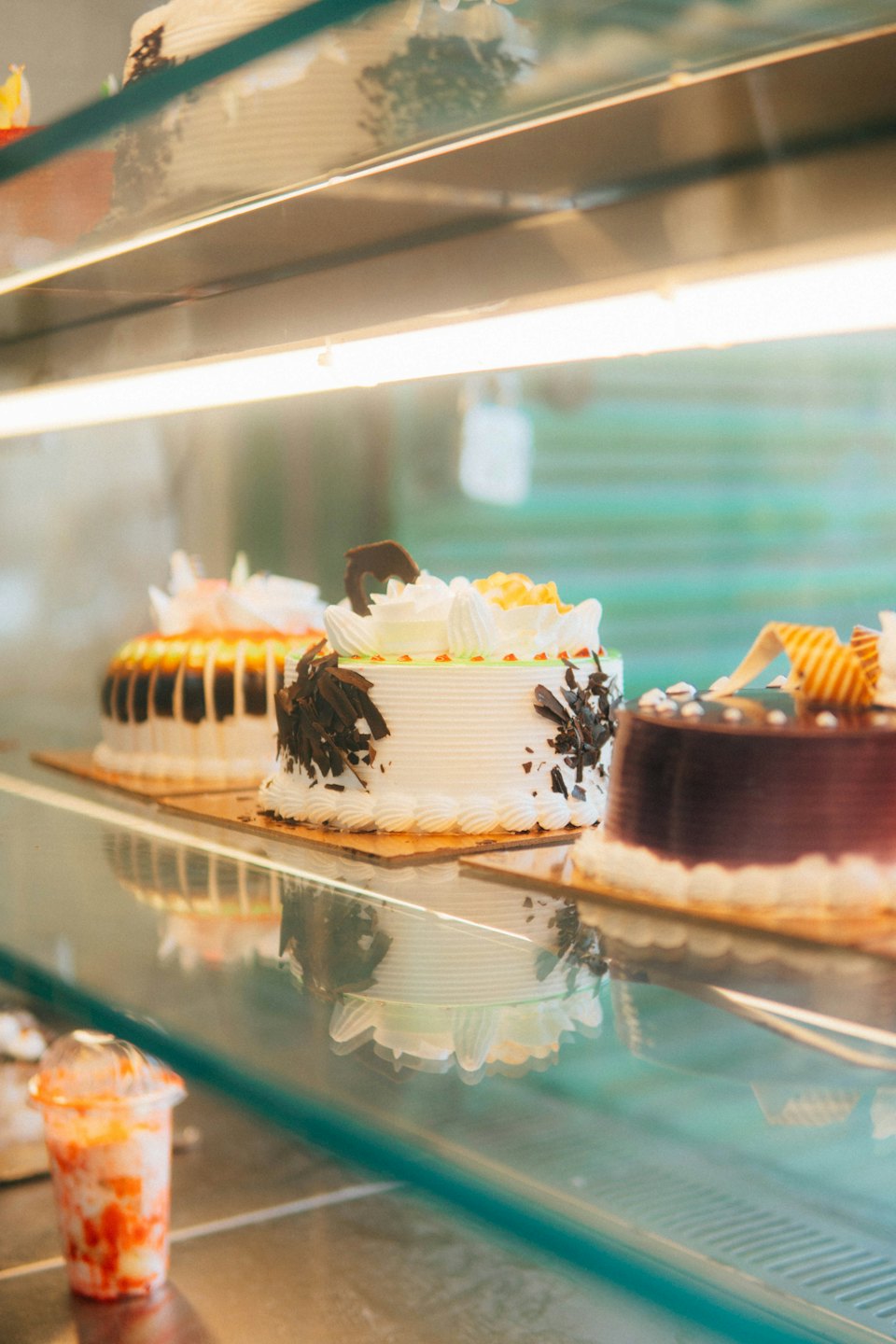Decorated cakes displayed in a refrigerated bakery case.